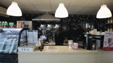 Bobruisk, Beyaz Rusya - 27 Nisan 2018: Bir kafe nin tezgahının arkasında kahve hazırlayan genç ve güzel bir kadın barmen
