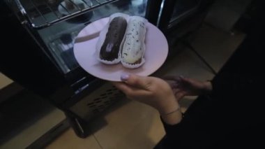Bir kadın elin insasının buzdolabında eclairs olan bir tabak koyup cam kapıyı kapatması