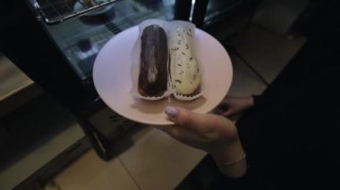Bir kadın elin insasının buzdolabında eclairs olan bir tabak koyup cam kapıyı kapatması