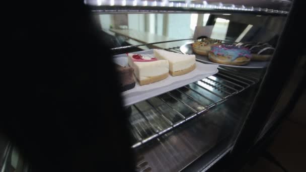 Eine weibliche Hand holt einen Teller mit Käsekuchen aus dem Kühlschrank — Stockvideo