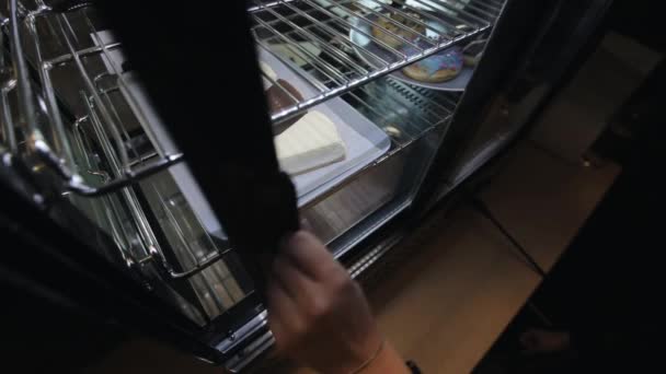 En kvinnlig hand som tar en tallrik med cheesecakes ur kylen — Stockvideo