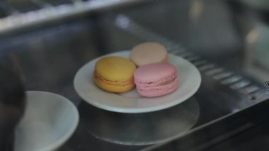 Bir dükkan penceresinin arkasında üç colo rful macaroons ile bir plaka yakın çekim