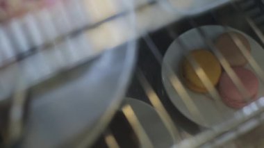 Bir dükkan penceresinin arkasında üç makaron ile bir tabak yakın çekim