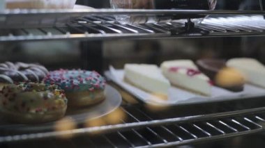 Bir dükkan penceresinin arkasında üç makaron ile bir tabak yakın çekim