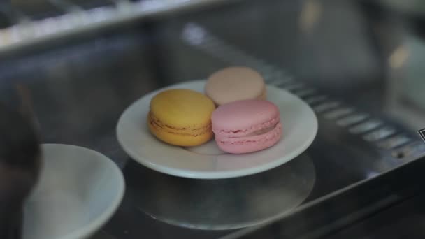 Um close-up de uma placa com três macaroons colo rful atrás de uma vitrine — Vídeo de Stock