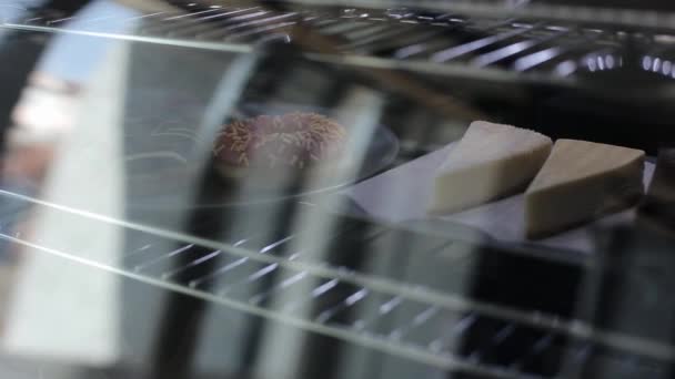En närbild av cheesecakes bakom glas i ett kafé kylskåp — Stockvideo