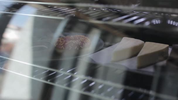Крупный план чизкейков за стеклом в холодильнике кафе — стоковое видео
