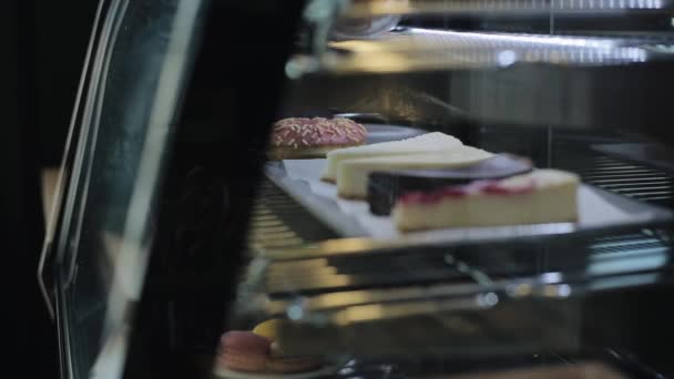 En närbild av cheesecakes bakom glas i ett kafé kylskåp — Stockvideo