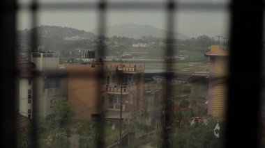 Tepelerde ve dağın eteğindeki vadide ağaçlarla kaplı şehrin güzel manzarası. Camdan kafesle ateş etmek. Bulanık arkaplan
