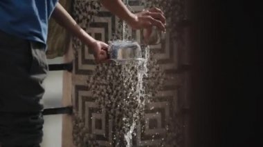 Katmandu, Nepal - 27 Kasım 2019: Hint Nepalli genç bir adamın demir kase su yıkadığı yakın plan. Sıçrama farklı yönlere uçuyor. Temizlik ve düzen kavramı