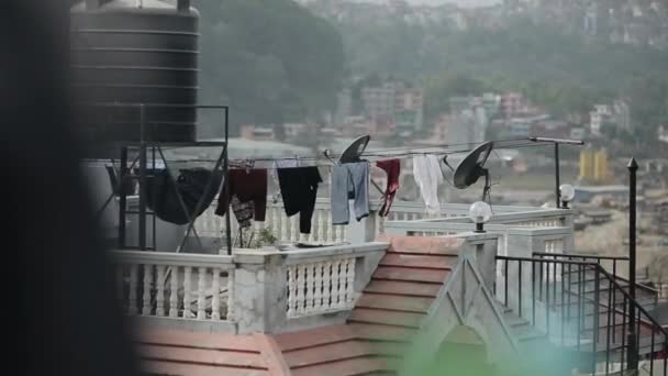 Vista de la azotea de un edificio de apartamentos en una ciudad asiática. Hay tanques de agua y antenas parabólicas en el techo. Hermosas vallas y ropa de secado en una cuerda — Vídeos de Stock