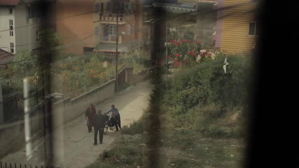 Katmandu, Nepal - 27 Kasım 2019: Nepalli Hintlilerin günlük yaşamları. Dar bir yolda erkekler ve kadınlar gider. Kamera dikkatleri dağın eteğindeki şehre çekiyor. — Stok video