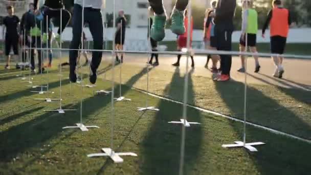 Minsk, Bielorrusia - 23 de junio de 2020: Entrenamiento por equipos de fútbol. Primer plano de las piernas jugadores de fútbol saltar por encima de las barreras en medio de la puesta de sol — Vídeos de Stock