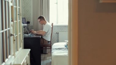 Amaçlı genç adam evde bilgisayarın başında çalışıyor. Dizüstü bilgisayarında yazmayı bitirir ve odadan çıkar. Yakın plan.