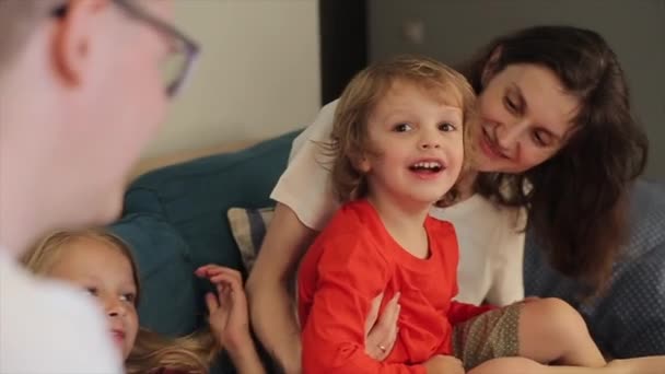두 자녀가 있는 한 우호적 인 가족 이방의 소파에 앉아 있다. 어린 소년은 카메라 에 손가락으로 카메라 를 보여 행복하게 웃는다. 클로즈업 — 비디오