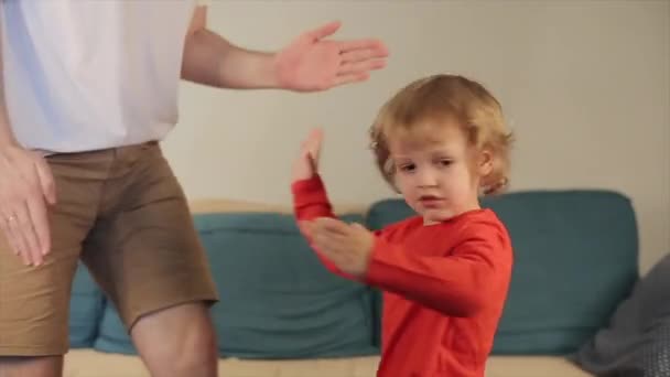 Padre se está divirtiendo con su hijo pequeño, que están juntos bailando en la habitación un divertido baile robot. Primer plano — Vídeo de stock