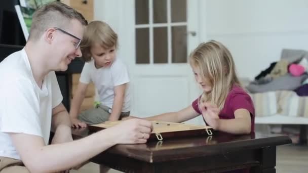 Papà e bambini giocano a un antico gioco da tavolo cinese Vai e papà sorride mentre sua figlia riflette sulla prossima mossa. Vista da un lato. Primo piano — Video Stock