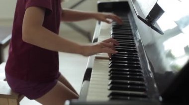 İlham verici küçük güzel kız notaya bakar ve klasik piyano müziği çalar. Yandan bak. Kamera yakın plandan genel bir plana yöneliyor. Yakın plan.