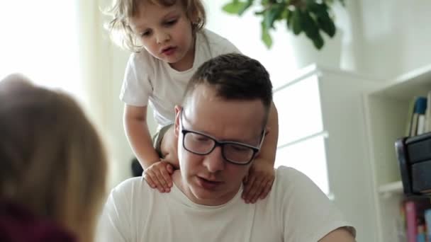 Önemseyen bir baba, küçük oğlu omuzlarına tırmanırken bir oyun sırasında kızıyla konuşur. Yakın plan. — Stok video