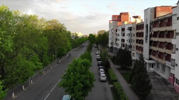 Footage from a drone of a city road with cars standing on it near an apartment building surrounded by trees. Fast shooting speed — Stock Video