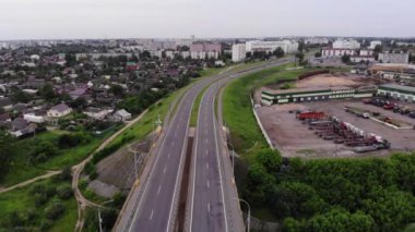 Endüstriyel binaların ve banliyölerin yanından geçen ve yaz aylarında yüksek apartmanlı bir mahalleye çıkan geniş otobanın tepesinden manzara