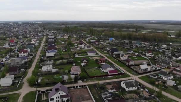 Panoramic view from the air of a large cottage village with private lands and the emphasis on a group of people in the yard of one of the houses — Stock Video