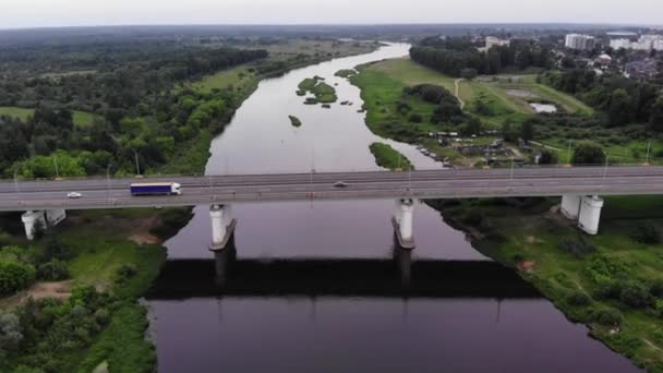 A birds-eye view of the city standing on the river bank and cars passing over the bridge. Panorama of cityscape and beautiful nature near the city — Stock Video