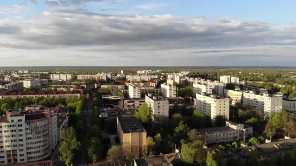 Vista de pájaro de la ciudad con edificios residenciales y centros comerciales entre los árboles sobre el fondo del cielo de verano. Disparo lento — Vídeo de stock