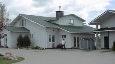 Güzel kır evi avluda açık gri renkte. Genç bir adam askıda kıyafet taşıyor ve telefonda konuşuyor.