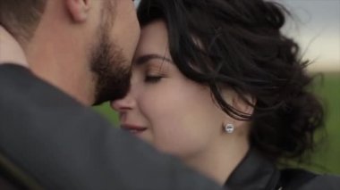 Nazik ve sevecen yeni evliler doğada ayakta durmayı benimsiyor. Rüzgar gelinlerin saçlarını savurur. Güzel bir çift. Yakın plan. Yavaş çekim