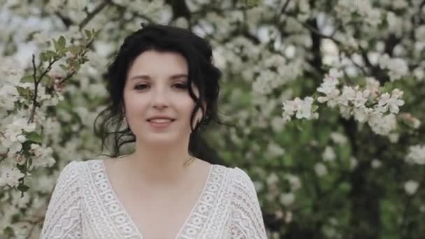 A gentle young girl with a calm smile walks through the blossoming spring garden. Close-up. Slow-motion — Stock Video