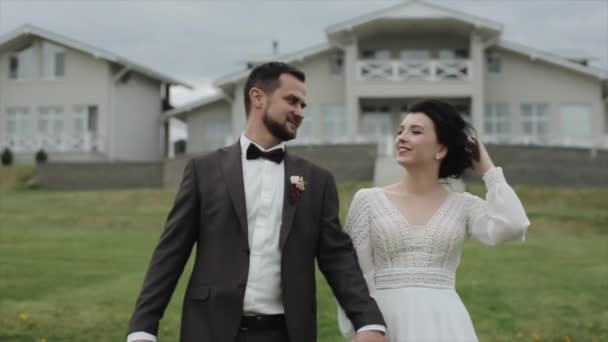 Un jeune couple heureux de jeunes mariés se câlinent et s'embrassent lors d'une promenade dans un domaine rural. Gros plan. Mouvement lent — Video