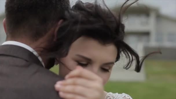 Heureux jeunes mariés dansent leur première danse dans la nature par une journée d'été venteuse. Un gros plan du visage des mariées. Les mariés vue arrière. Mouvement lent