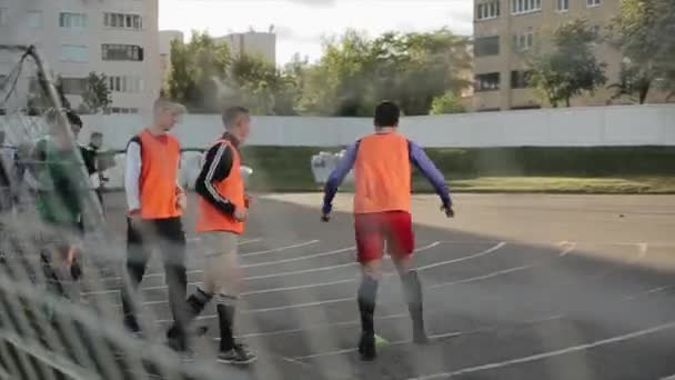 白俄罗斯明斯克- 2020年6月23日：足球运动员热身。在运动场上跑步锻炼.穿过大门格子射击。模糊的前背景。四.后续行动 — 图库视频影像