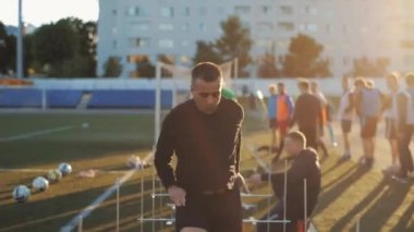 Futbol mu? Antrenman. Futbol sahasında bir engelin üzerinden atlayan bir futbol takımının yakın plan oyuncusu.
