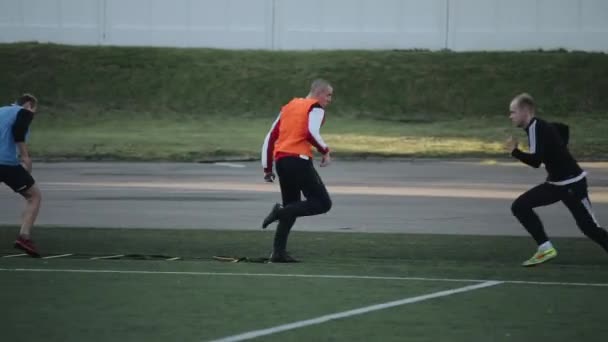 Minsk, Λευκορωσία - 23 Ιουνίου 2020: Οι παίκτες της ποδοσφαιρικής ομάδας εκπαιδεύονται και εκτελούν διακρατικές ασκήσεις υπό την καθοδήγηση του προπονητή στο γήπεδο ποδοσφαίρου. Η κάμερα ακολουθεί αθλητές — Αρχείο Βίντεο