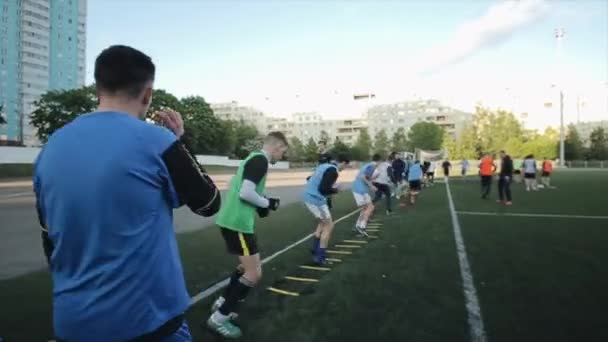 Minsk, Bielorrusia - 23 de junio de 2020: Entrenamiento por equipos de fútbol. Los jugadores se turnan para hacer ejercicios en la escalera de alta velocidad cumpliendo con los requisitos del entrenador. Primer plano — Vídeo de stock