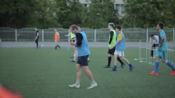 Минск, Беларусь - 23 июня 2020: Футболисты на тренировках медленно идут и вытирают пот после бега на скорости по футбольному полю. Вид сбоку. Крупный план — стоковое видео