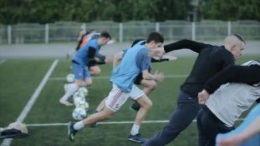 Futbol kulübünün antrenmanında. Oyuncular futbol sahasında hızlı koşarlar. Kamera odak değiştiriyor. Yakın plan. Model Gerçekleştirildi