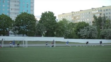 Futbol antrenmanındaki futbolcular futbol sahasında hızlı koştuktan sonra yavaşça ter silerler. Yandan bak. Yakın plan.