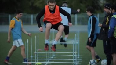 Futbol takımının oyuncuları futbol sahasında antrenman yapıyor ve koçun sinyalinde engellerle koşuyor. Yakın plan. Model Gerçekleştirildi