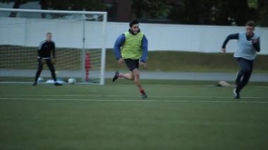 Futbol kulübü eğitimi. Oyuncuların bacaklarının yakın çekimi bariyerin üzerinden atlıyor ve sahada koşuyor. Yavaş çekim