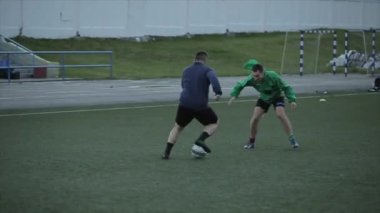 Futbol takımı eğitimi. Oyuncular bariyerlerin üzerinden atlayıp sahada topla koşan karmaşık hız egzersizleri yapıyorlar. Yakın plan.
