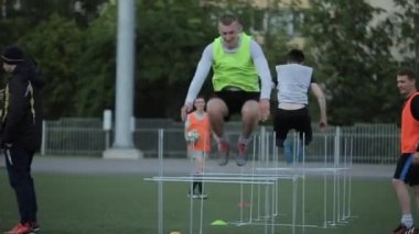 Futbol takımının oyuncuları antrenman sırasında sahada oyun anları ve top sürme pratiği yapıyorlar. Yakın plan.