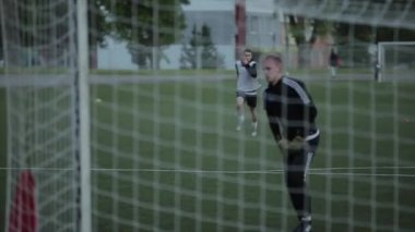 Futbol takımı eğitimi. Oyuncular farklı egzersizler yapar. Ağın arkasından kapının arkasından ateş ediyor. Kamera topu seyrediyor. Yakın plan. Model Gerçekleştirildi