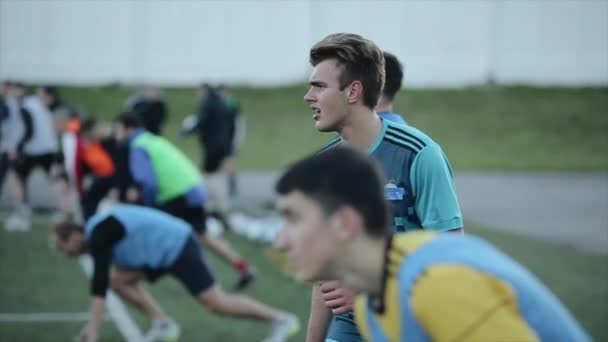 Ejecutando el entrenamiento del club de fútbol. Los jugadores corren a toda velocidad en el campo de fútbol. La cámara cambia de enfoque. Primer plano — Vídeos de Stock