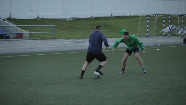 Voetbal team training. Spelers voeren complexe snelheidsoefeningen uit die over de slagbomen springen en met de bal over het veld rennen. Close-up — Stockvideo