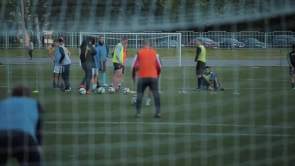 Allenamento della squadra di calcio. I giocatori fanno esercizi diversi. Sparare da dietro il cancello attraverso la rete. La telecamera sta guardando la palla. Primo piano. Modello Realizzato — Video Stock