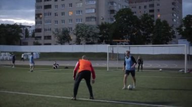 Şehir stadyumunda futbol takımının akşam antrenmanı. Ağın arkasından kapının arkasından ateş ediyor. Arka planda bulanıklık. Yakın plan.