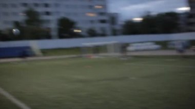 Şehir stadyumunda futbol takımının akşam antrenmanı. Ağın arkasından kapının arkasından ateş ediyor. Arka planda bulanıklık. Yakın plan.